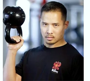 Dr. Mark Cheng holding a kettlebell in the rack position at the shoulder