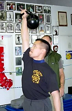 Dr. Mark Cheng pressing a kettlebell overhead